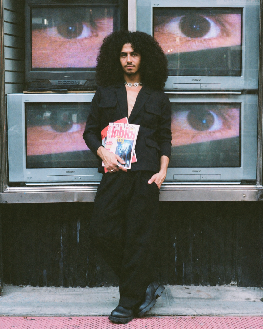 Figure holding magazines in front of televisions showing eyes