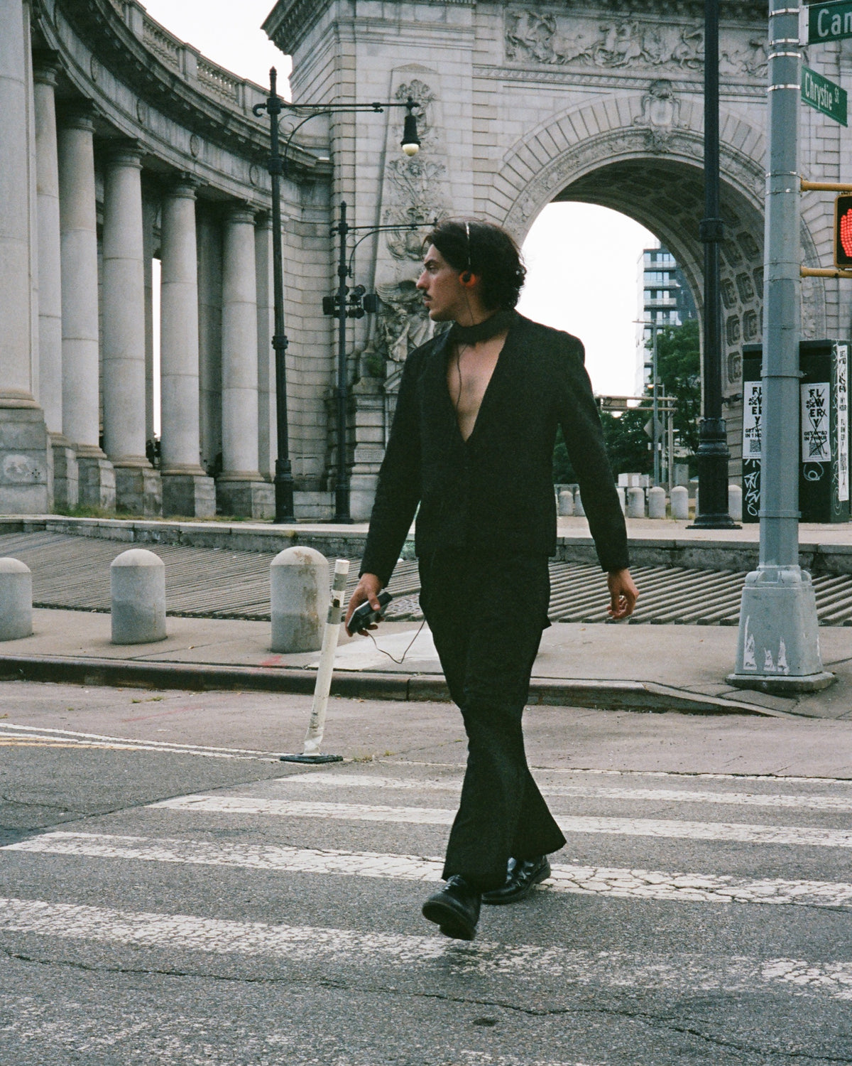Figure in a black mardôm suit crossing beneath a stone arch downtown