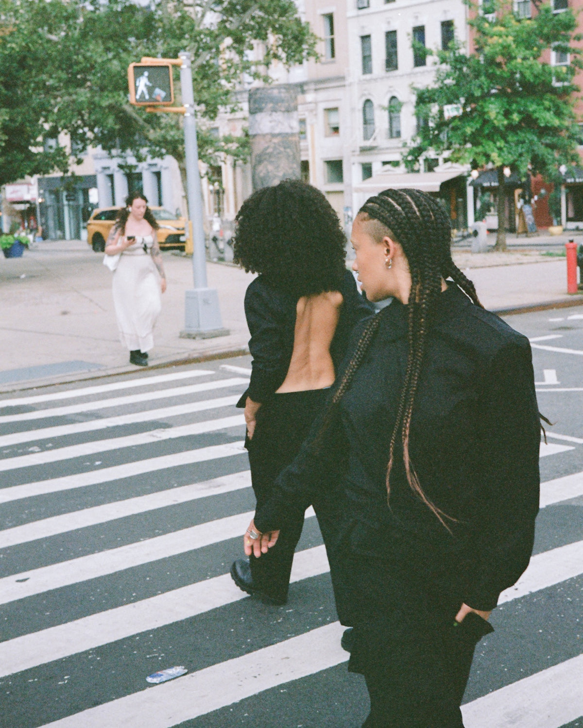 Two figures walking away across a crosswalk