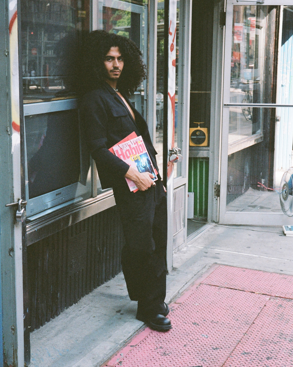 Figure holding magazines in a storefront doorway