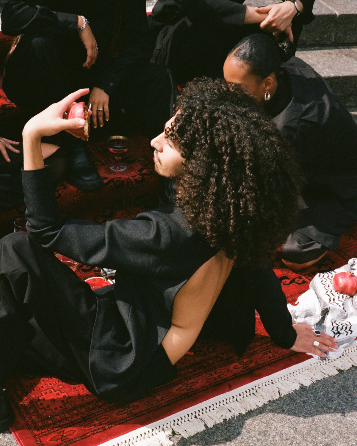 Figure reclining on a red rug on stone steps