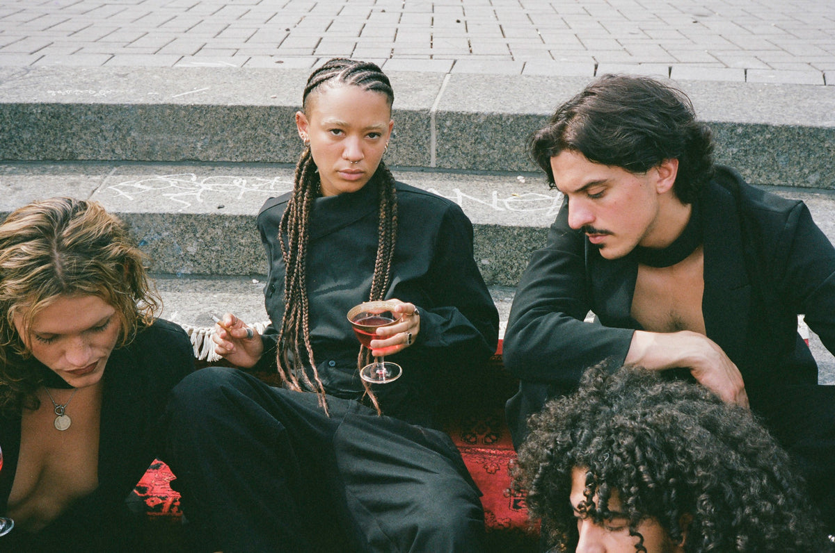 Group seated on stone steps, one holding a glass of wine