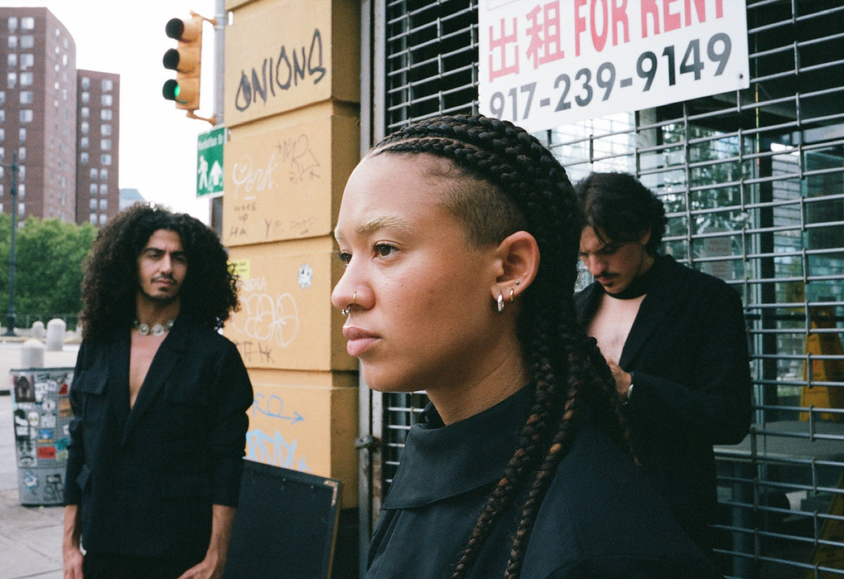 Three figures in black outside a storefront