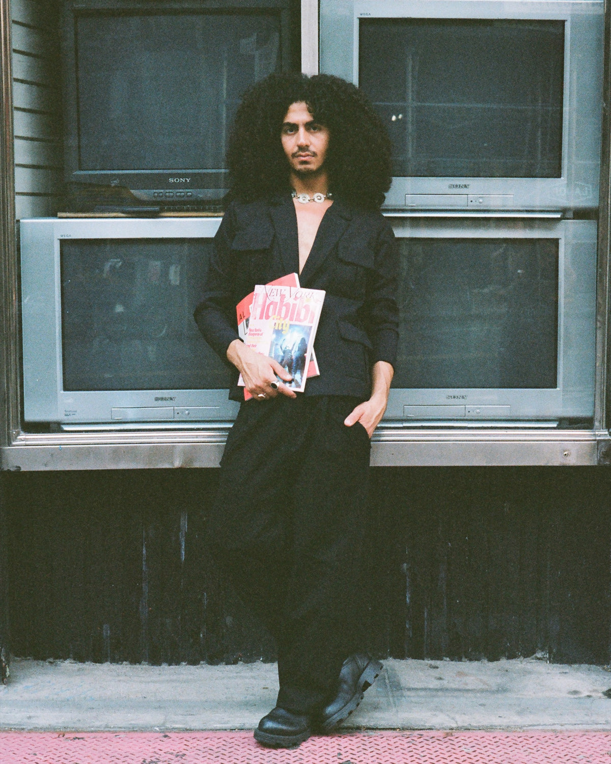 Figure holding magazines in front of televisions showing eyes